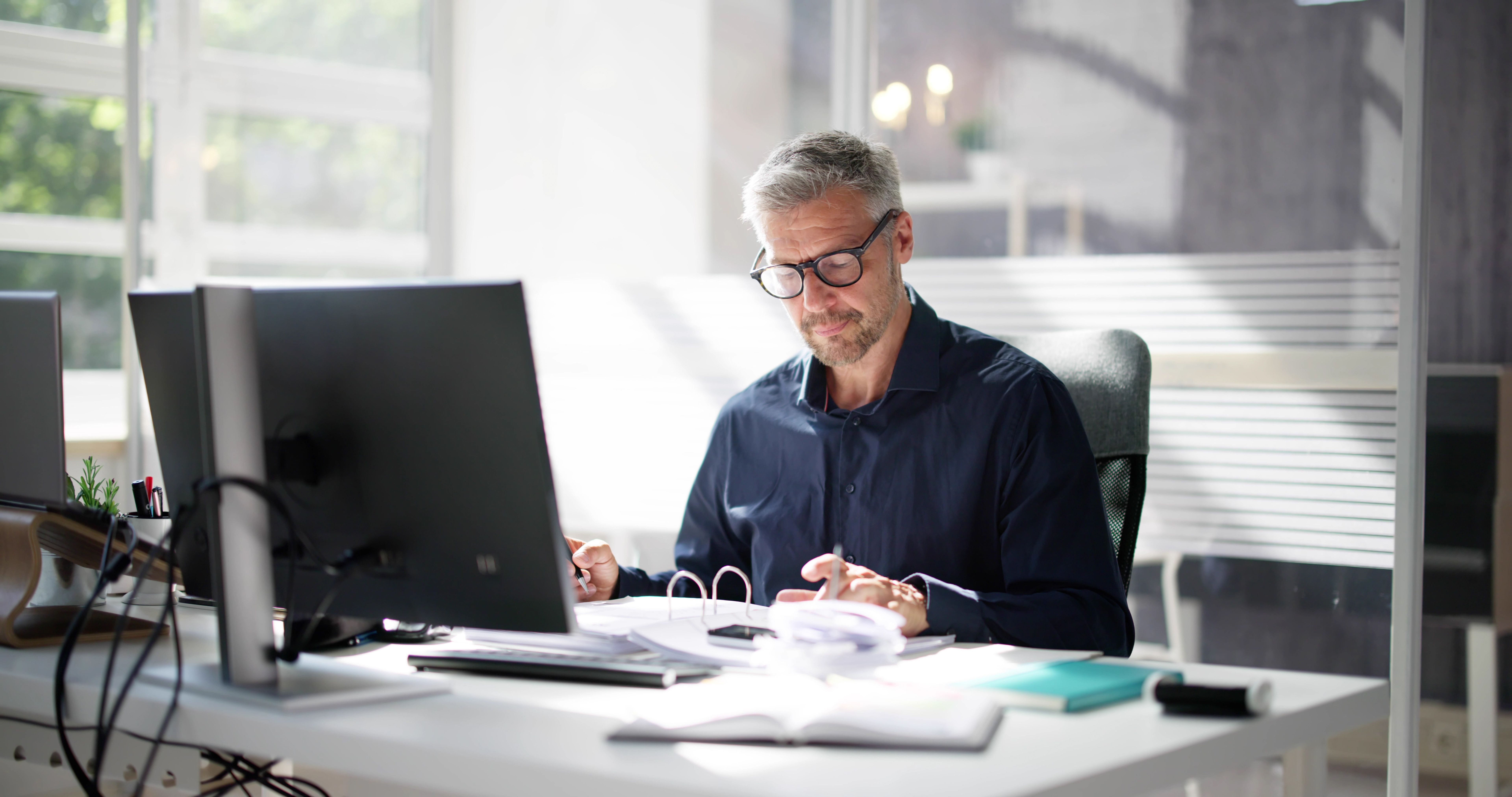 Consultant aan een bureau in donkerblauw colbert, focus op het werk